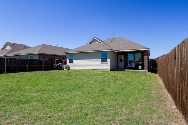 back of property with brick siding, a yard, and a fenced backyard