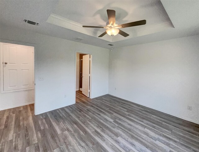 spare room with visible vents, a raised ceiling, ceiling fan, and wood finished floors