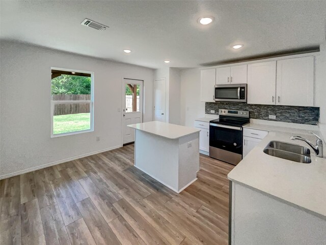 kitchen featuring a sink, appliances with stainless steel finishes, light countertops, a kitchen island, and light wood-type flooring