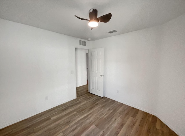 empty room featuring ceiling fan, baseboards, wood finished floors, and visible vents