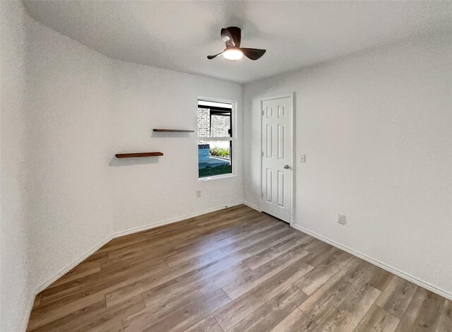 empty room with wood finished floors, ceiling fan, and baseboards