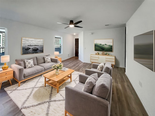 living room featuring wood finished floors, a ceiling fan, visible vents, and baseboards