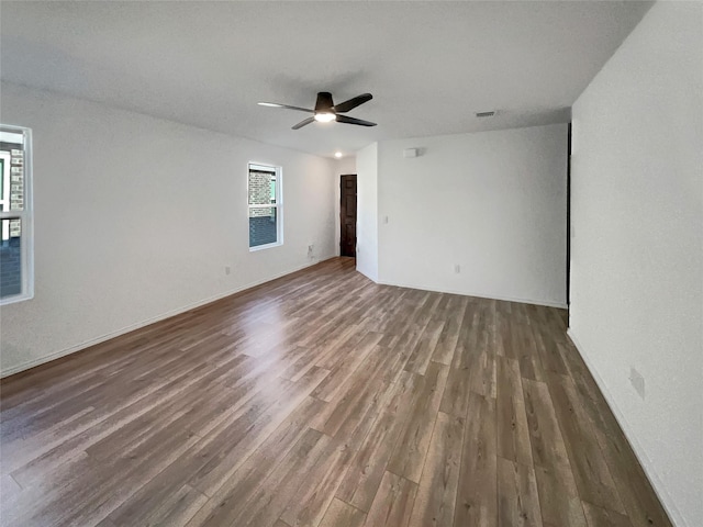 unfurnished room featuring wood finished floors, a healthy amount of sunlight, and ceiling fan