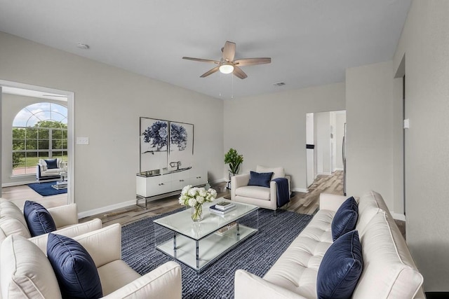 living area with visible vents, baseboards, ceiling fan, and wood finished floors