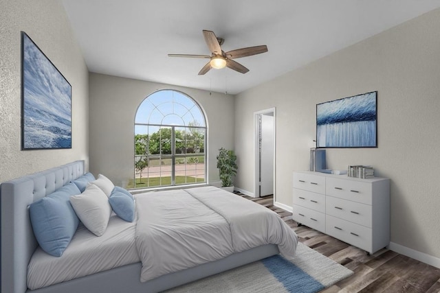 bedroom featuring baseboards, a ceiling fan, a textured wall, and wood finished floors