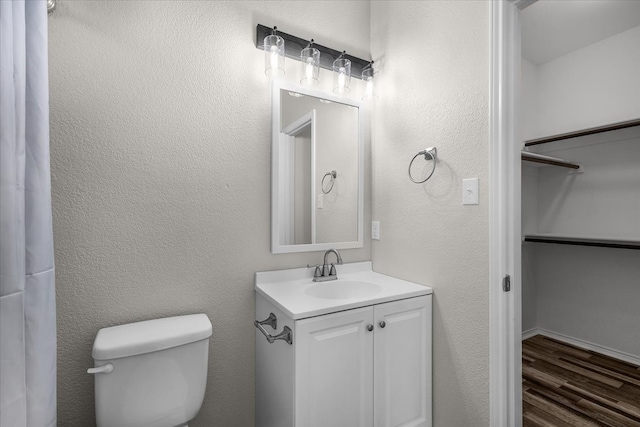 bathroom with toilet, wood finished floors, and vanity