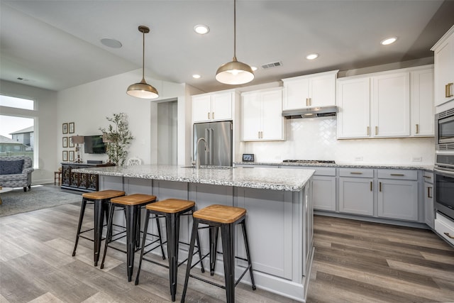 kitchen with backsplash, visible vents, a sink, appliances with stainless steel finishes, and dark wood-style flooring