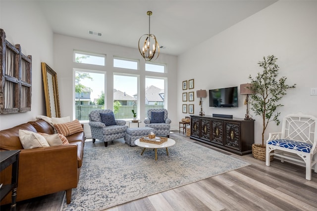living area featuring a high ceiling, a notable chandelier, wood finished floors, and visible vents