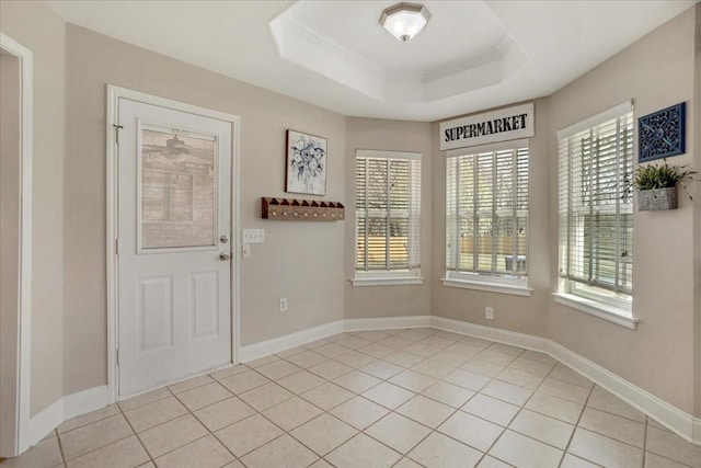 entryway featuring a raised ceiling, a healthy amount of sunlight, ornamental molding, and light tile patterned floors