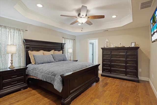 bedroom with a tray ceiling, visible vents, ornamental molding, and recessed lighting