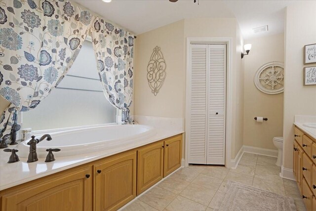 bathroom featuring visible vents, toilet, vanity, a closet, and a garden tub