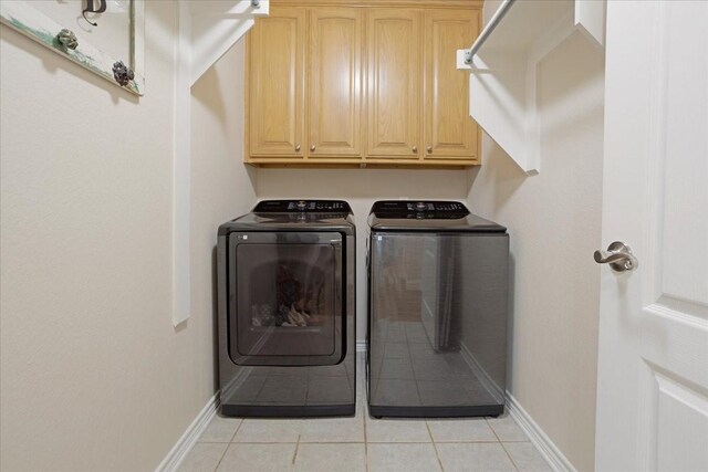 clothes washing area with light tile patterned floors, baseboards, cabinet space, and independent washer and dryer