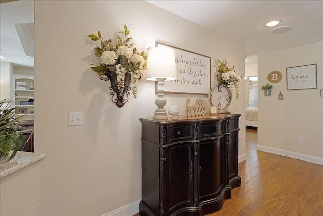 hallway with baseboards, light wood finished floors, and recessed lighting