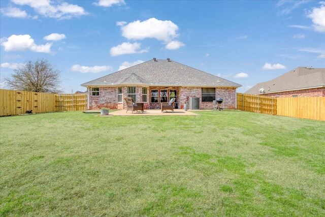 rear view of property featuring a patio area, a fenced backyard, brick siding, and a yard