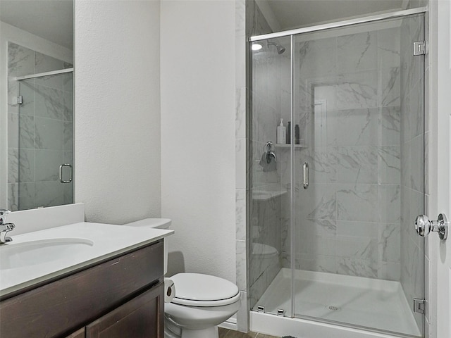bathroom featuring toilet, vanity, and a stall shower
