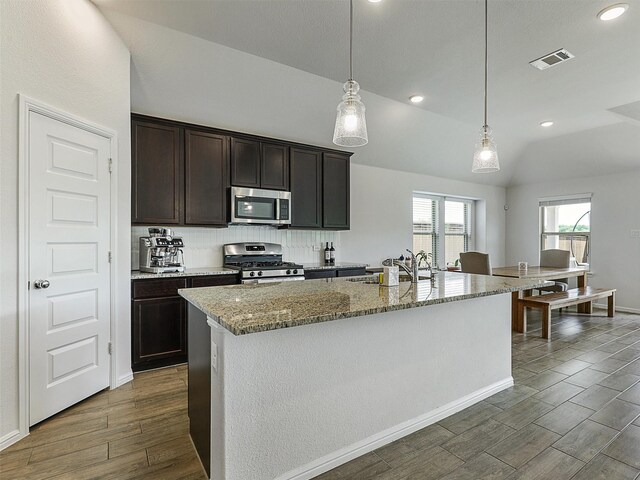 kitchen featuring stainless steel appliances, a sink, dark wood-style flooring, visible vents, and light stone countertops