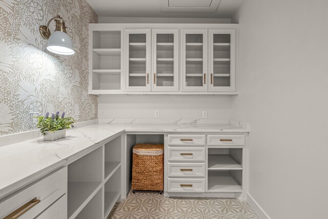 interior space with built in desk and wallpapered walls