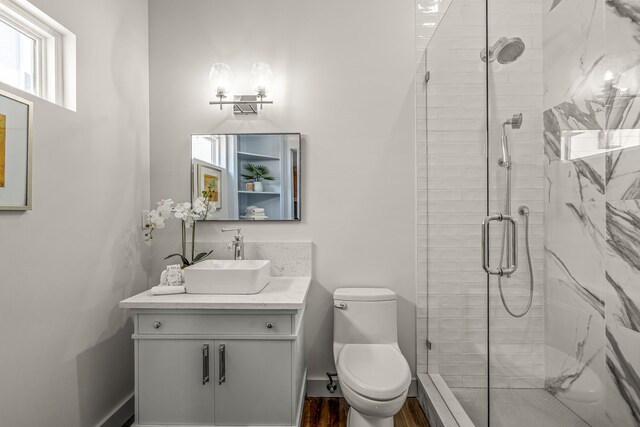 full bathroom with wood finished floors, toilet, vanity, baseboards, and a stall shower