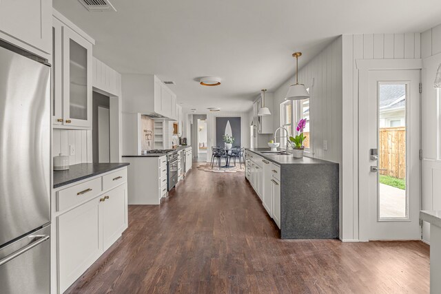kitchen featuring dark countertops, stainless steel refrigerator, dark wood-style floors, and a sink