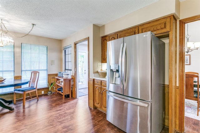 kitchen with an inviting chandelier, dark wood-style floors, brown cabinetry, and stainless steel fridge with ice dispenser