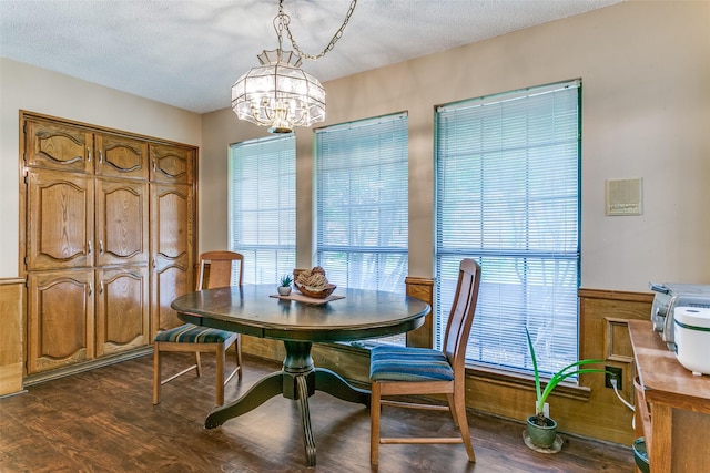 dining area featuring dark wood finished floors, a textured ceiling, and a notable chandelier