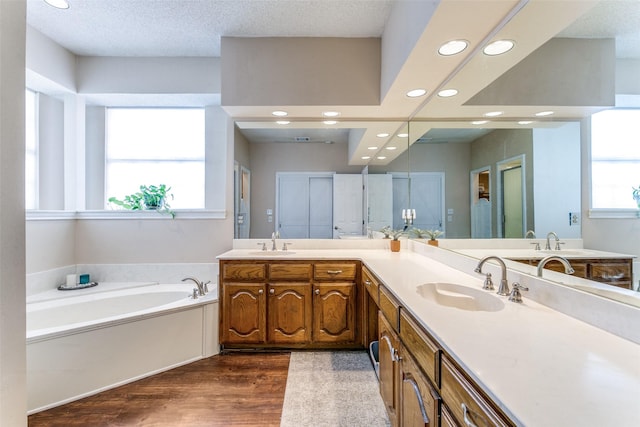 bathroom with recessed lighting, double vanity, wood finished floors, and a sink