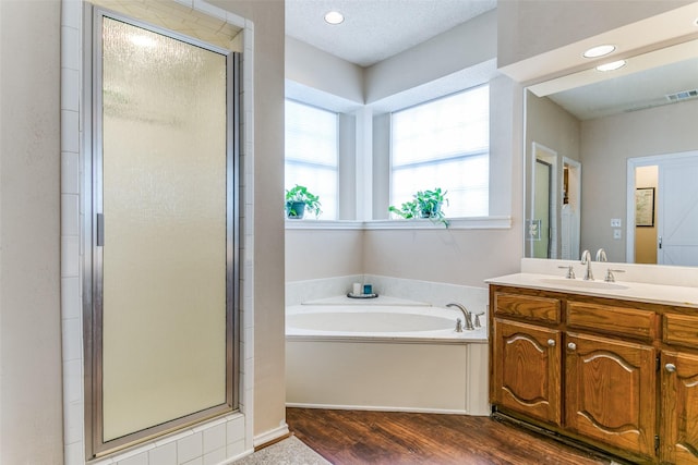 full bathroom with a garden tub, wood finished floors, vanity, and a stall shower