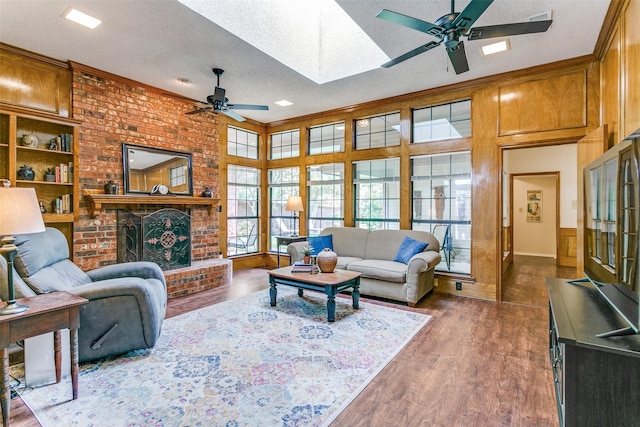 living room featuring a skylight, a ceiling fan, a textured ceiling, and dark wood finished floors