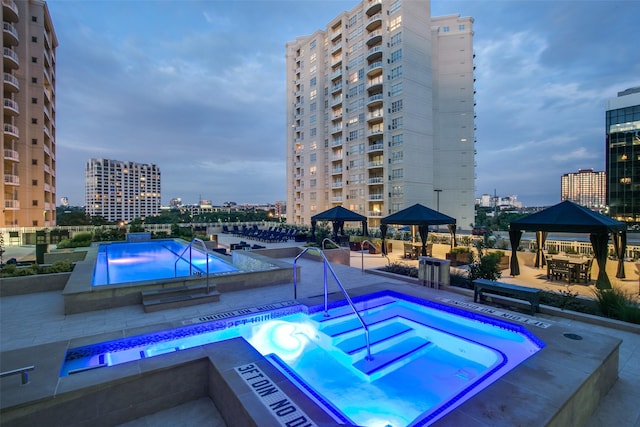 view of swimming pool with a gazebo, a hot tub, and a city view