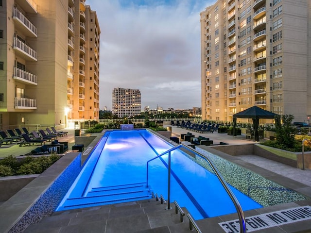 community pool with a gazebo, a city view, and a patio