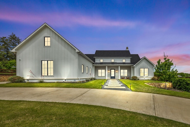 modern farmhouse featuring board and batten siding, covered porch, a yard, metal roof, and a standing seam roof