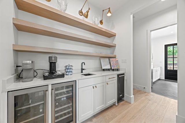 bar with wet bar, beverage cooler, a sink, and light wood-type flooring