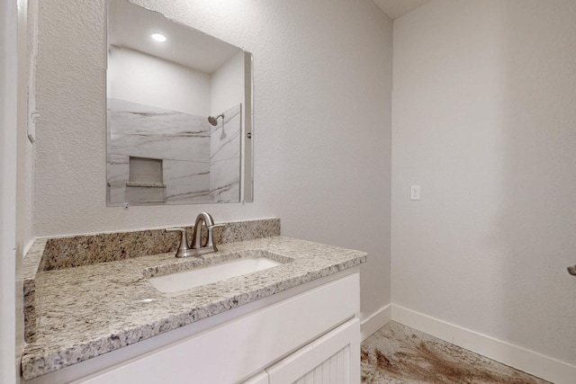 full bath with a marble finish shower, vanity, baseboards, and marble look tiles
