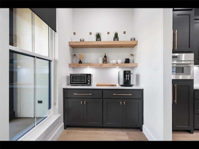 612 Glade Stream Ct, Azle, TX 76020 - bar with stainless steel oven, baseboards, a toaster, and light wood-type flooring
