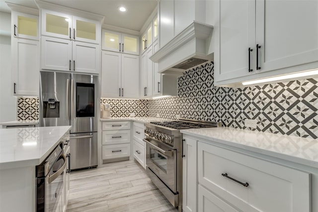 1301 Meadows Ave, Lantana, TX 76226 - kitchen with appliances with stainless steel finishes, tasteful backsplash, white cabinetry, and custom range hood