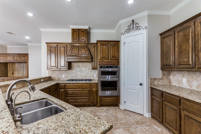 kitchen with a sink, custom exhaust hood, stainless steel appliances, light stone counters, and recessed lighting