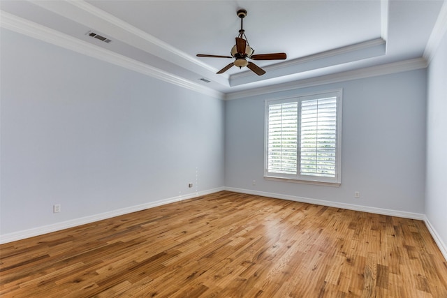 empty room with a tray ceiling, light wood-style floors, baseboards, ceiling fan, and crown molding