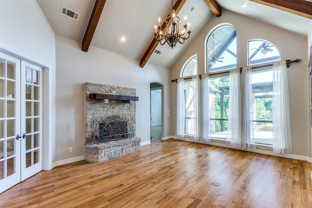 unfurnished living room with beam ceiling, french doors, wood finished floors, arched walkways, and a fireplace
