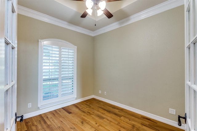 unfurnished room with ornamental molding, ceiling fan, wood finished floors, baseboards, and healthy amount of natural light