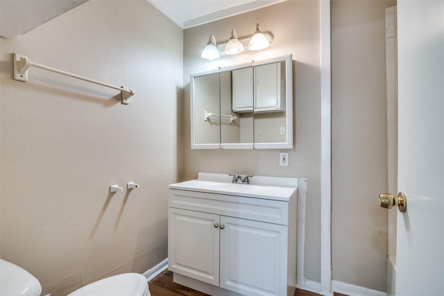 bathroom featuring toilet, vanity, wood finished floors, and baseboards