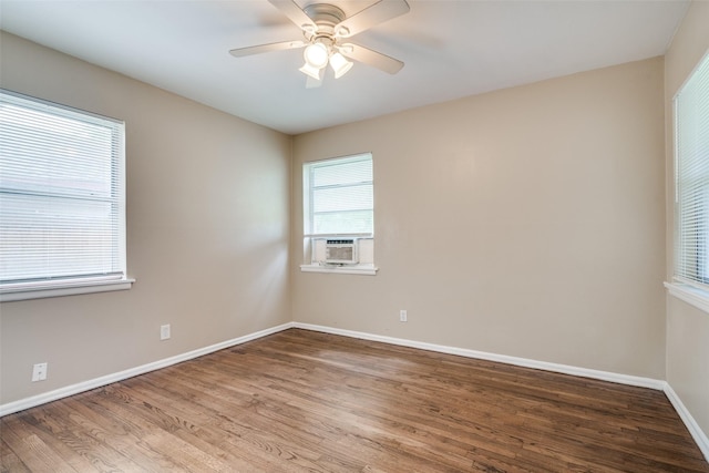 empty room featuring cooling unit, baseboards, a ceiling fan, and wood finished floors