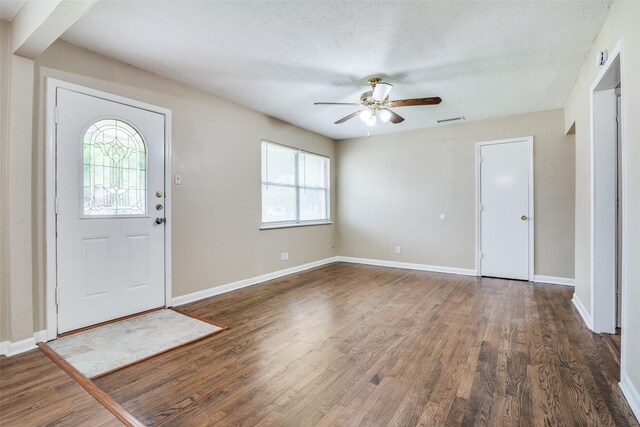 foyer entrance with wood finished floors, visible vents, a ceiling fan, and baseboards