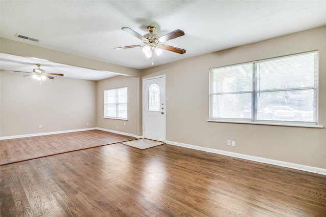 foyer featuring baseboards, a ceiling fan, wood finished floors, and visible vents