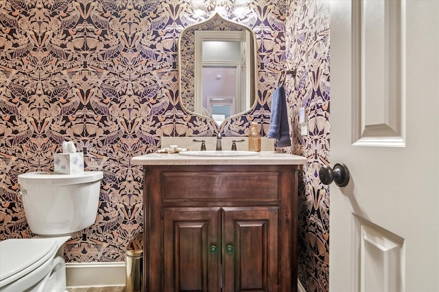 half bathroom with wallpapered walls, vanity, and toilet