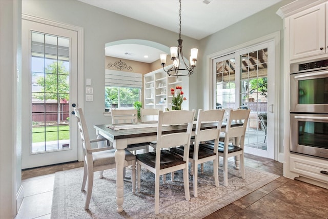 dining room with arched walkways, a notable chandelier, and light tile patterned flooring
