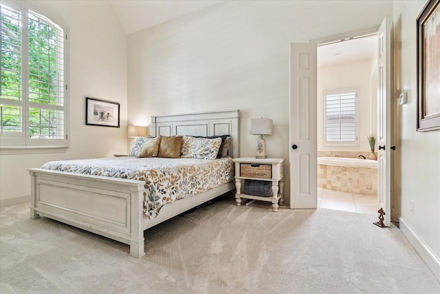bedroom with ensuite bath, vaulted ceiling, baseboards, and light colored carpet