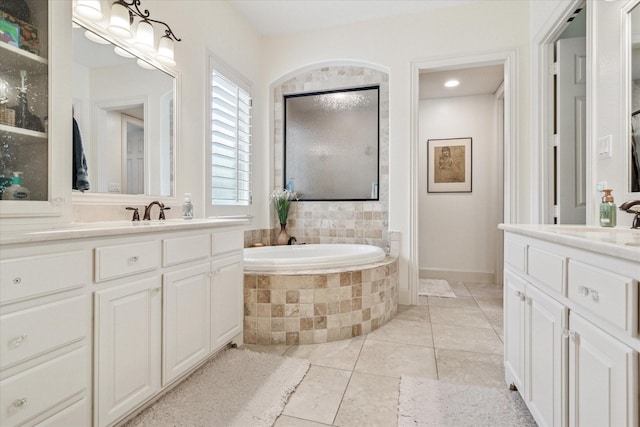 full bath featuring two vanities, a bath, tile patterned flooring, and a sink