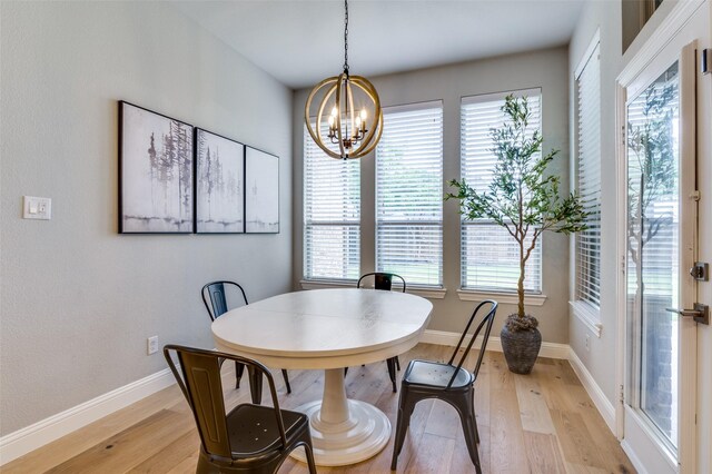 dining area with a chandelier, light wood-style flooring, and baseboards