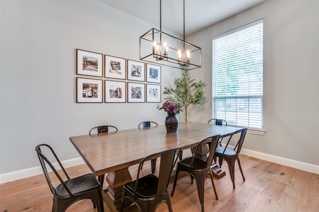 dining space with light wood-type flooring, baseboards, and a notable chandelier