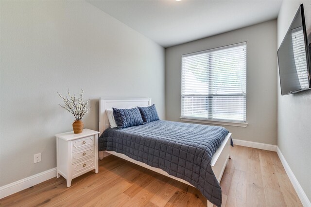 bedroom featuring baseboards, multiple windows, and light wood-type flooring